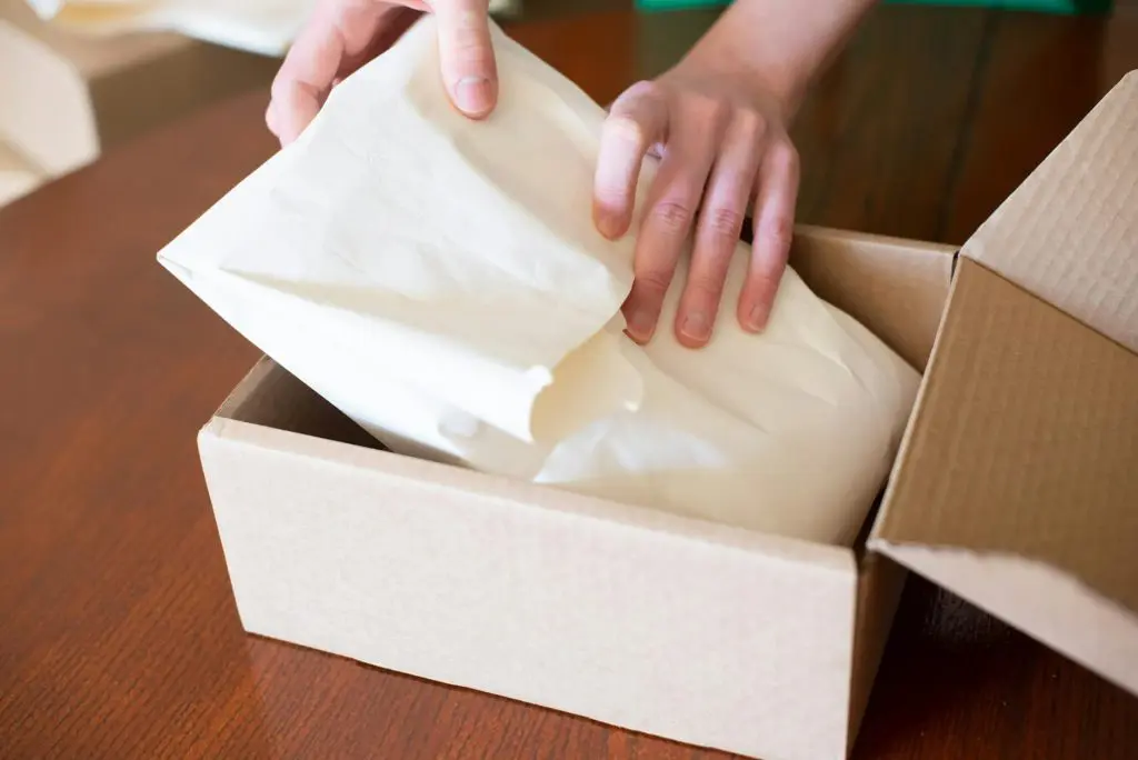 close up of person packing an order into a cardboard box, strip club store
